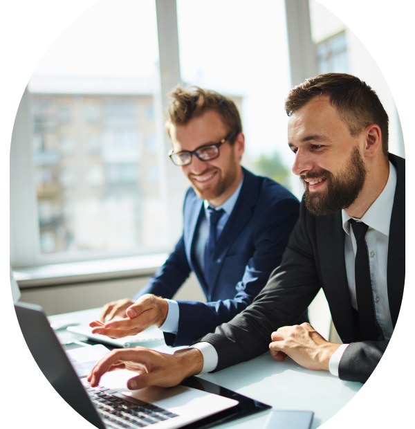 Two smiling men sitting down and looking at a laptop in a bright office. Learn about your compliance obligations for 2025 as a Canadian employer.